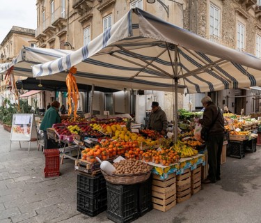 Syracuse, Italy, 28 December, 2023: greengrocer selling fruit and vegetables to customers in the