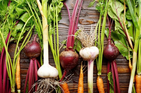 Vegetarian background of fresh organic beetroots green garlic and carrots on kitchen wooden rustic