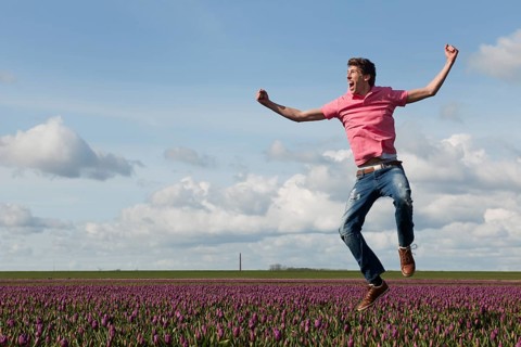 Young man is jumping above the typical dutch tulips