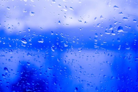 Raindrops on a window, illustrating gray and rainy weather during the day. Black and white