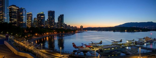 Harbour view at sunset with seaplanes and illuminated skyline in the background, Vancouver, British