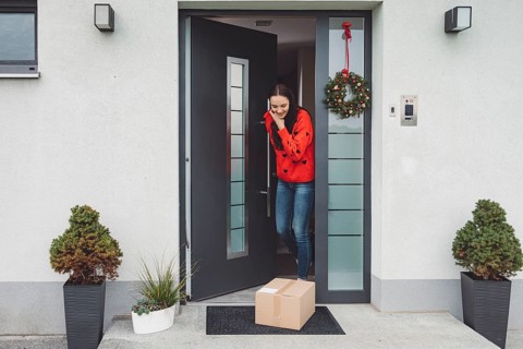 Cheerful young woman excited over a package she just received. Woman getting her christmas gift in