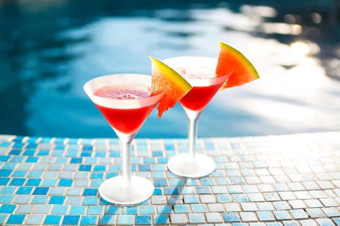 Glasses of watermelon cocktail with watermelon slices near the pool