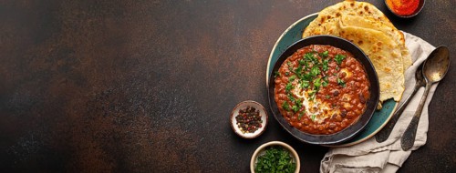 Traditional Indian Punjabi dish Dal makhani with lentils and beans in black bowl served with naan