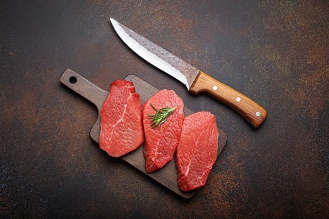 Three raw uncooked meat beef top sirloin steaks on wooden cutting board with rosemary on wooden