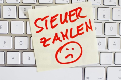 A note on the keyboard of a computer as a reminder: Pay tax Austria