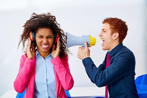 Businessman shouting in megaphone to african executive with scared expression