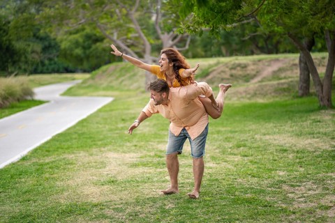 Man giving his girlfriend a piggyback ride in a park
