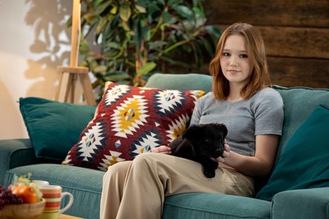 A young woman happily enjoys quality time with her adorable puppy in a stylish and inviting living