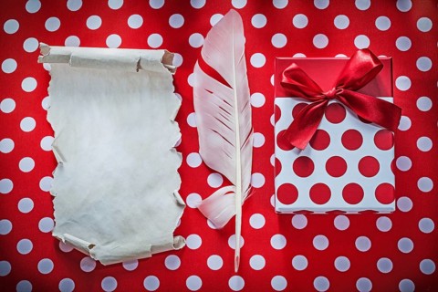 Present box vintage sheet of paper plume on polka-dot red table cloth celebrations concept