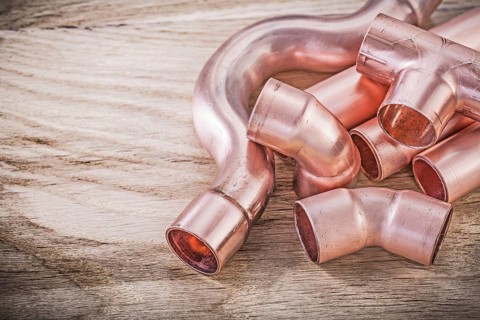 Copper water pipe connectors on wooden board plumbing brassware concept