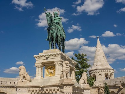 Equestrian statue with lions and a surrounding tower in front of a blue sky, budapest, danube,