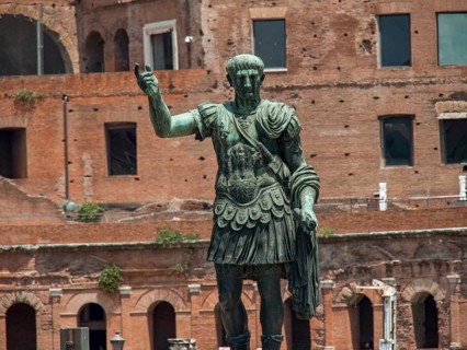 Bronze statue of a soldier in front of an ancient building in sunny weather, Rome, Italy, Europe