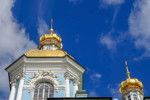 Baroque building with a blue façade and magnificent golden domes against a deep blue sky in St.