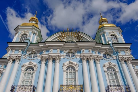 A magnificent church with golden domes, a blue façade and white columns