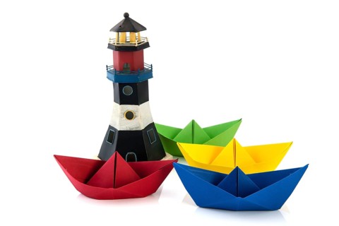 Colorful folded paper boats with lighthouse isolated over white background