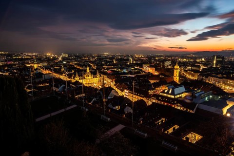 Sunset over the old town of Graz, view from the Schlossberg, illuminated tower of the Franciscan