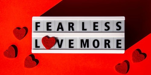 Lightbox with text FEAR LESS LOVE MORE. Motivational Words Quotes Concept with red hearts. Colorful