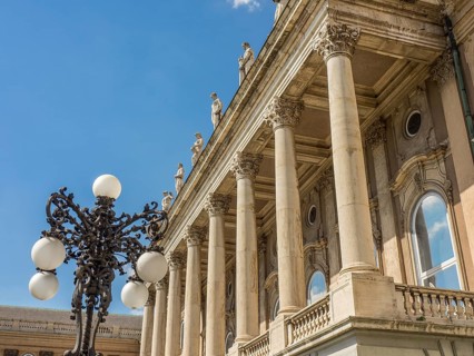 A building with classical columns, decorated with an ornate street lamp and blue sky in the