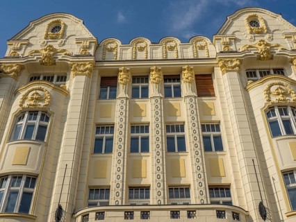 Historic building with ornate façade, stucco work and gilded elements under a blue sky, bratislava,
