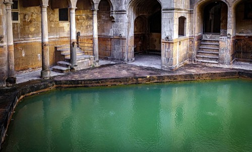 Water and buildings in an old roman bath in the city of Bath in the united kingdom england