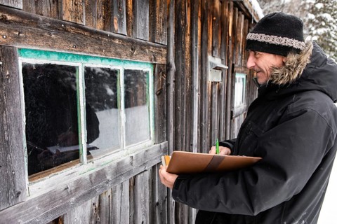 Middle aged home Inspector taking notes on a notebook with leather cover during an outdoor