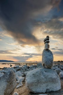 Stone sculpture on the shore of a lake at sunset with dramatic sky, Seegarten, Allensbach, Lake