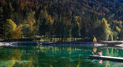 Kranjska Gora, Slovenia, 18 October, 2021: tourists enjoy relaxing on the wooden dock at Lake Jasna