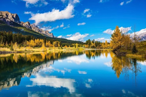 Concept hiking. Canmore, near Banff. Jagged mountains and red-orange trees are reflected in the