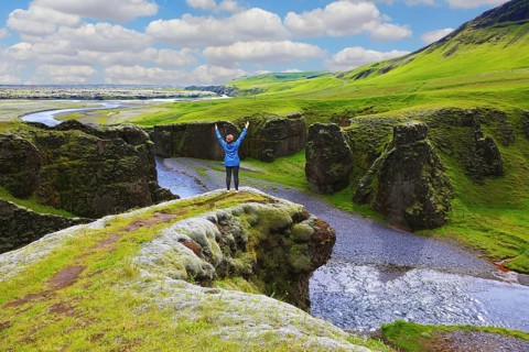 Fantastic country Iceland. Enthusiastic woman - tourist on a rock canyon Fjadrargljufur