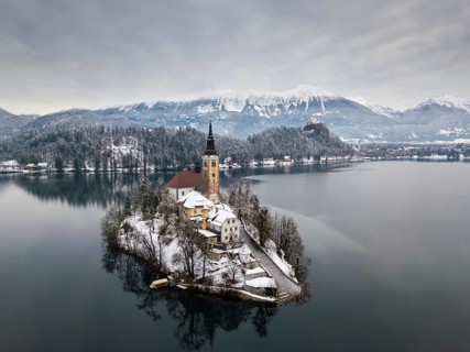Aerial shot of lake Bled on a calm winter morning with snow