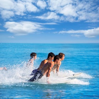 Boys teen surfers surfing running jumping on surfboards at the beach