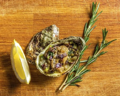 Salad in oyster served with greens and lemon on a wooden background