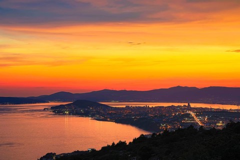 View of a city at dusk with vivid colours in the sky and reflecting water, Split, Dalmatia,