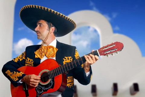 Charro Mariachi singer playing guitar in Mexico with white house background