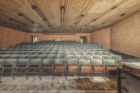 Dusty, empty lecture theatre with green rows of seats and visible bricks, Institute of Molecular