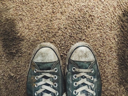 Pair of worn out black sneakers on brown carpet