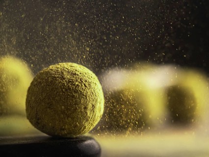 Homemade truffles candy with matcha tea powder in green tea dust cloud over dark background. Copy