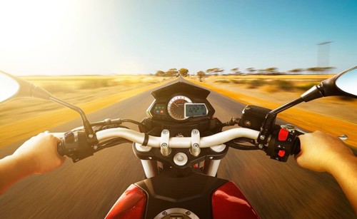 Biker driving a motorcycle rides along the country road, morning scene . First person angle view