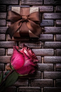 Red scented rose present box on wicker wooden place mat