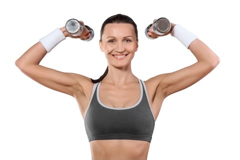 A sports woman with dumbbells looking at camera smiling isolated