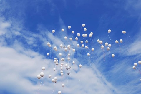 White balloons flying in clear blue sky
