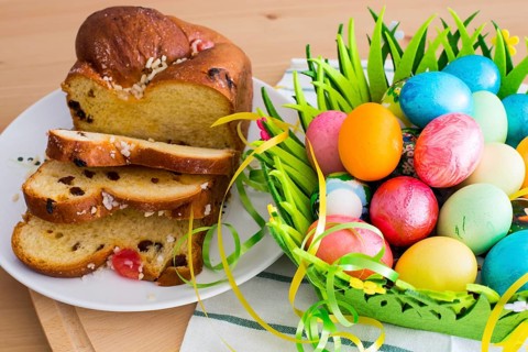 Still life with Nice spring yellow flowers, colorful Easter eggs and traditional Easter cake