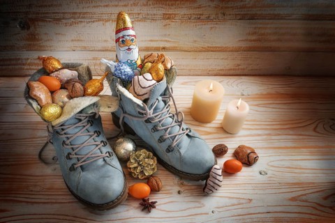 Boots filled with sweets, chocolate Santa and Christmas decoration on a wooden background with