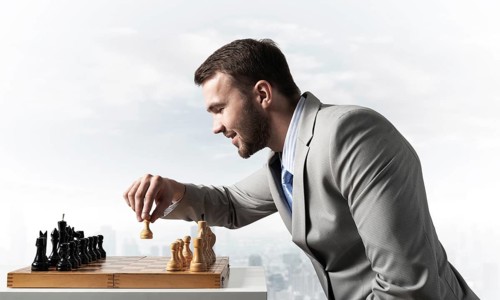 Concentrated businessman playing chess game. Successful management and leadership concept.