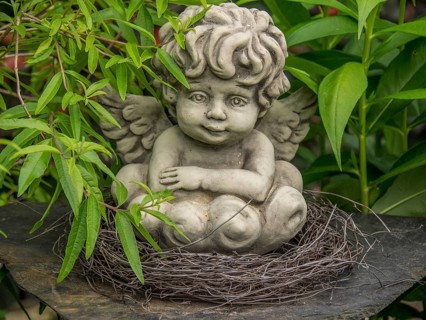 Angel statue in a nest of twigs, surrounded by green leaves in the garden, borken, münsterland,