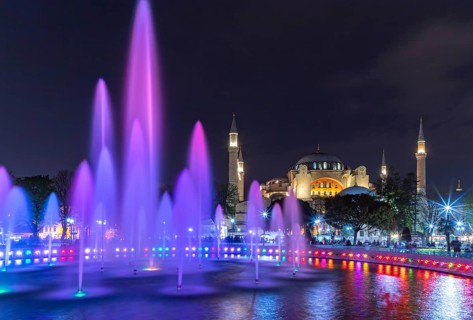 A picture of the Hagia Sophia and the colorful Sultan Ahmet Park Fountain at night