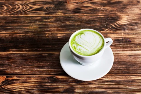 Top view of the cup Matcha latte on wooden background. The concept of green tea as an art