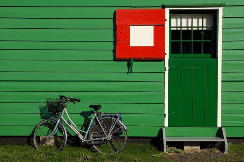 Bicycle parked in front of a green painted timbered house on the Dutch tourist attraction Zaanse