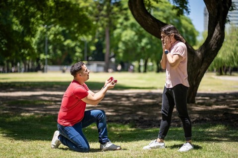 Young man surprising his boyfriend in a park with a wedding ring